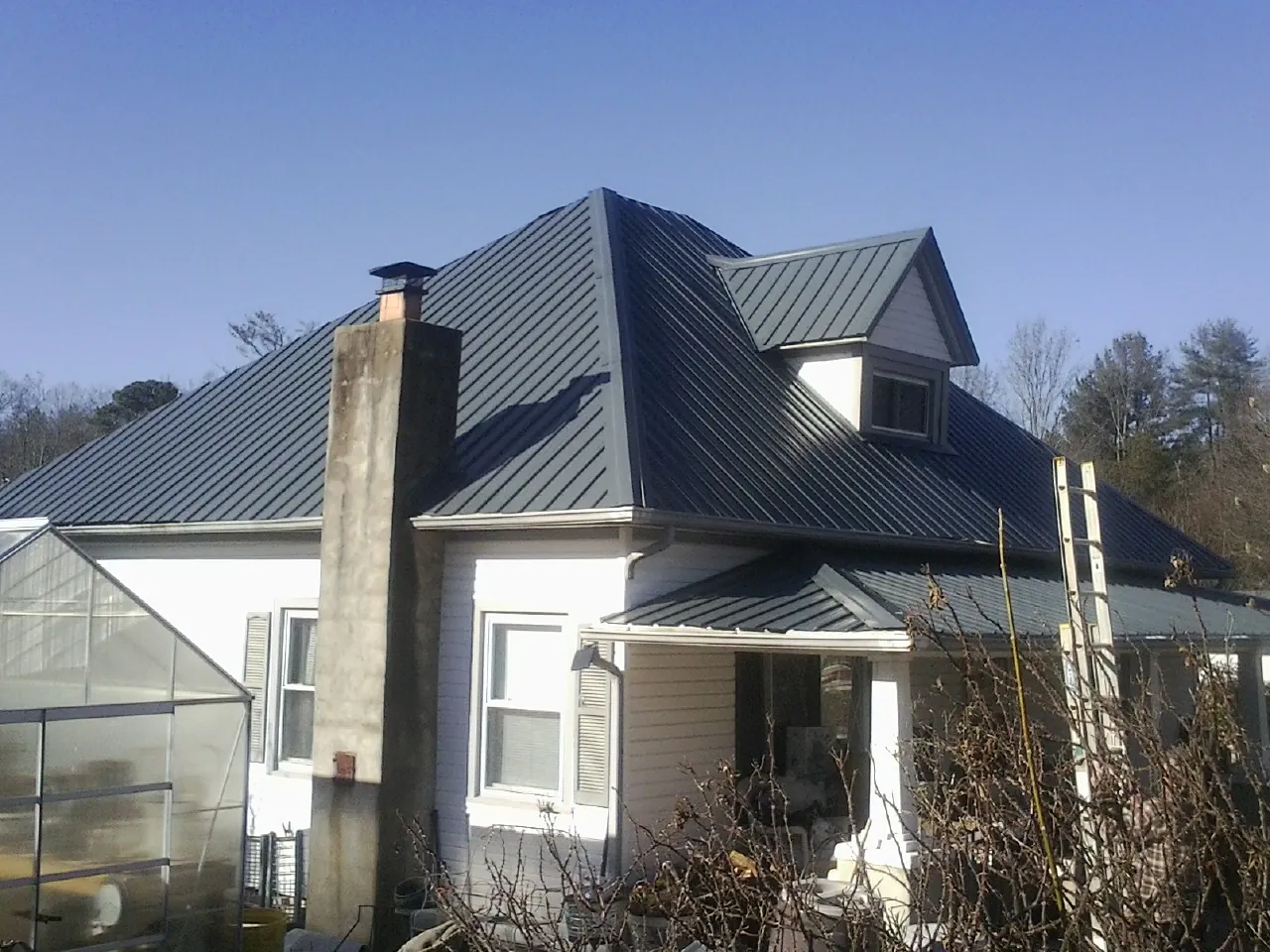 Dark blue standing seam metal roof on a white farmhouse with dormer — Slate & Tile Roof Repair by Roofing Brothers in Orcas