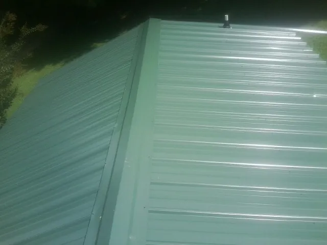 New green metal panels meeting at the ridge of a roof — Flat Roof Repair work by our crew in Orcas