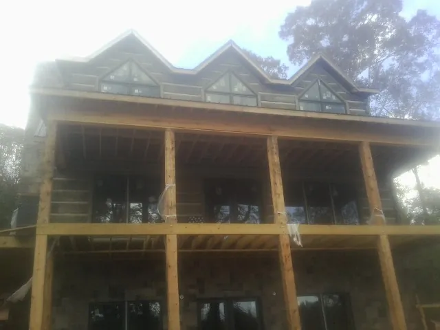 Dormers and porch framing on a large log home under construction — Roof Coating work by our crew in Orcas