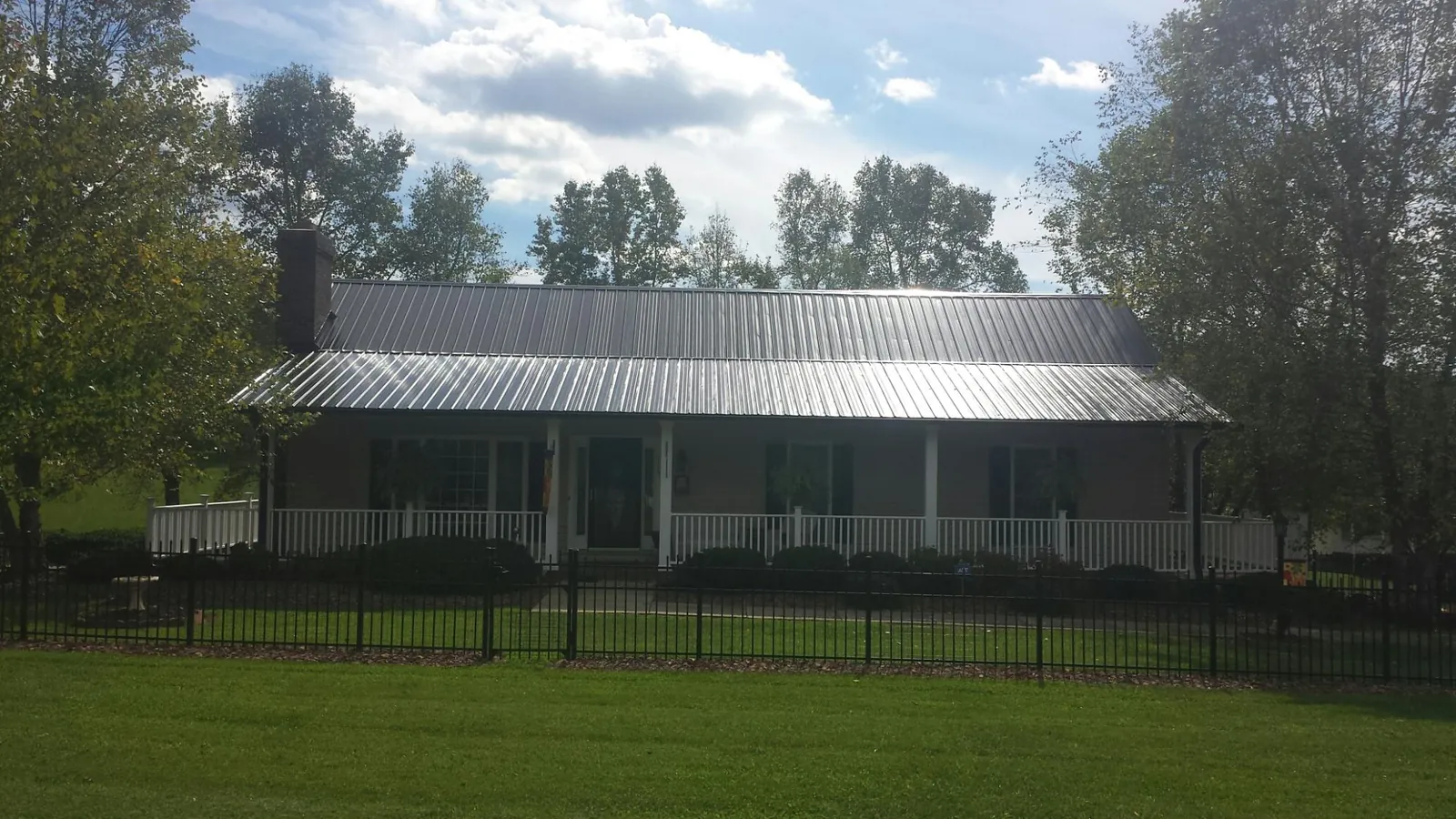 Gray metal roof on a brick ranch with a full width front porch — Gutter Guard Installation work by our crew in Orcas