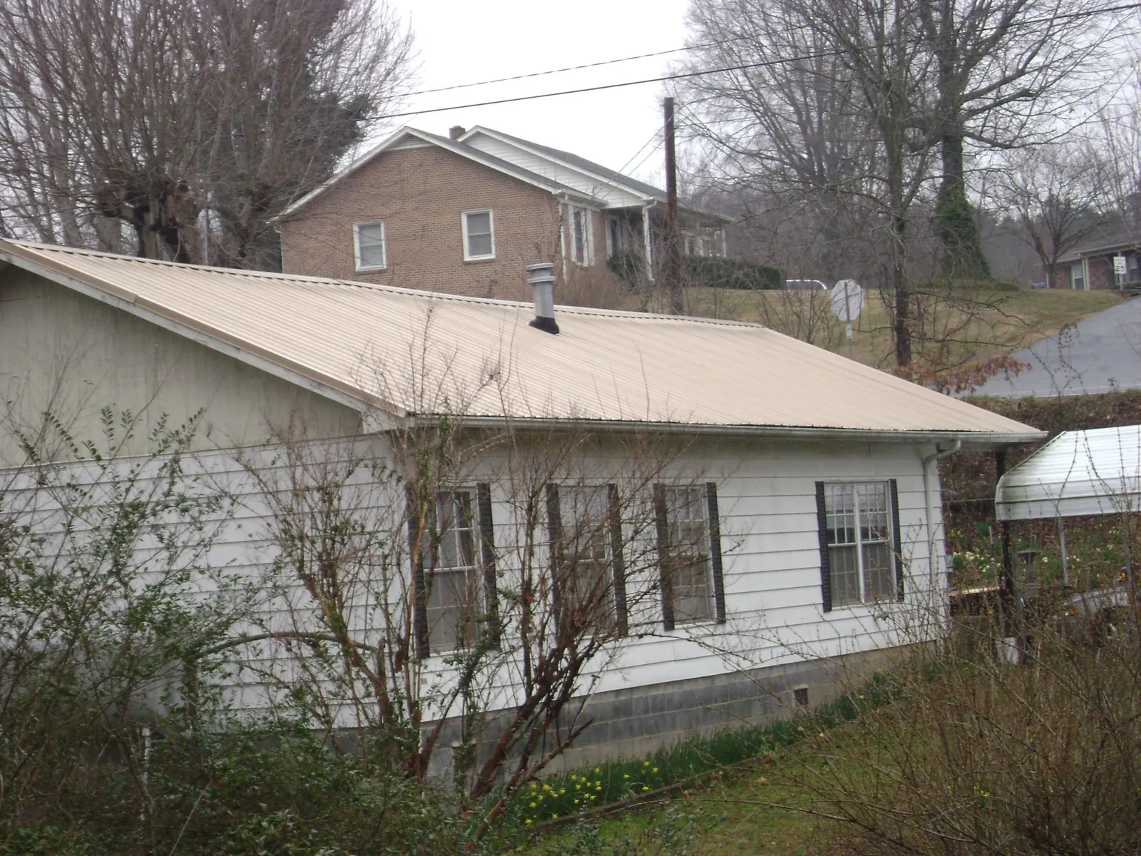 Tan metal roof on a white sided house set into a hillside — Commercial Roofing by Roofing Brothers in Orcas