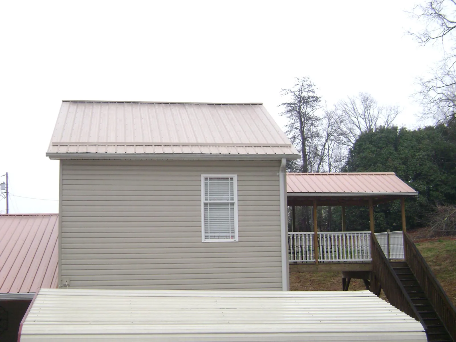 Tan metal roofs on a two story addition and attached porch, from a Roof Replacement job in Orcas