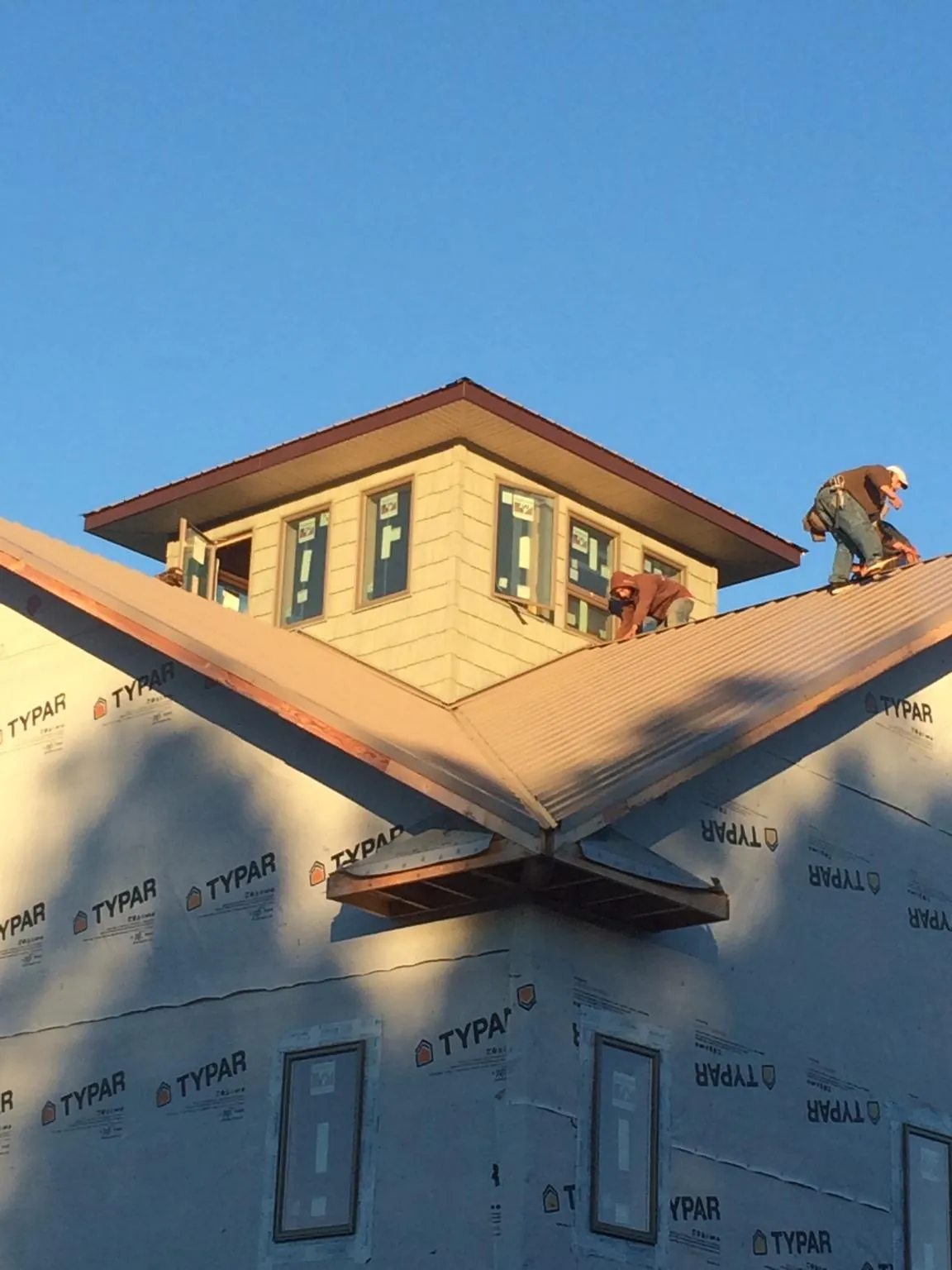 Roofers working around a rooftop cupola on a new metal roof at sunset — Roof Waterproofing in Orcas by Roofing Brothers